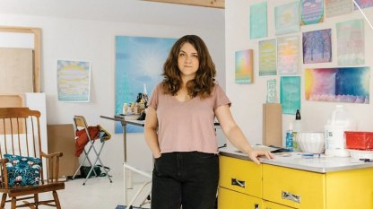 portrait of Amy Lincoln in her studio with paintings and studies on the walls behind her