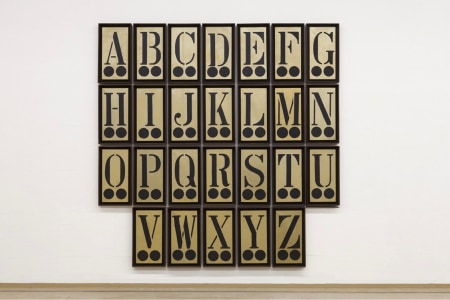 A painting consisting of twenty-six 24 by 12 inch gold panels, each with a different letter of the alphabet in black above to black circles. In the image the painting is displayed in four horizontal rows: the firs with the letters A through G, the second with the letters H through N, the third with the letters O through U, and the last with the letters V through Z.