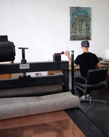 image of a man working at a desk with a painting above him