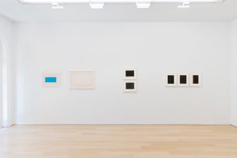 installation view of multiple works on paper in a white room