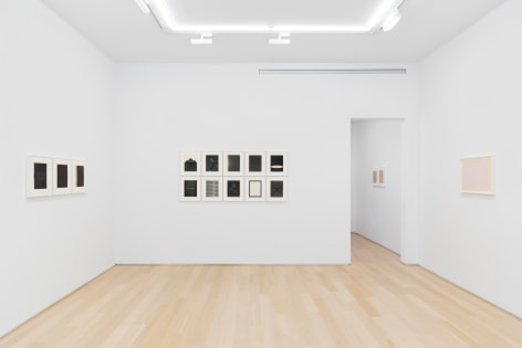 installation view of multiple works on paper in a white room