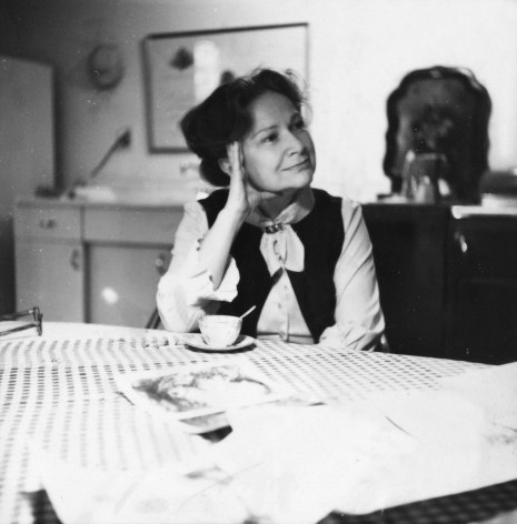 woman sitting at a table with artwork around her