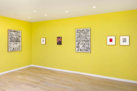 installation view of multiple works on paper and paintings in a yellow room