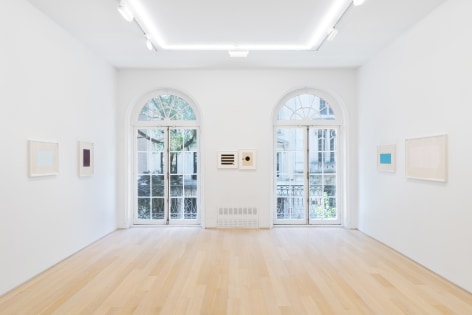 installation view of multiple works on paper in a white room