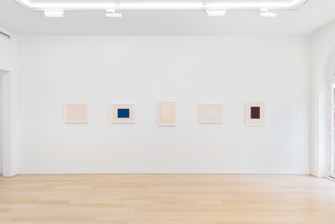 installation view of multiple works on paper in a white room