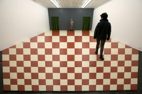 two people standing on red and white checkered optical illusion on gallery floor