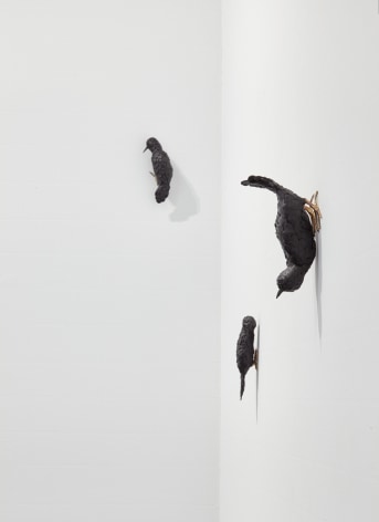 Three bird sculptures posed on gallery wall