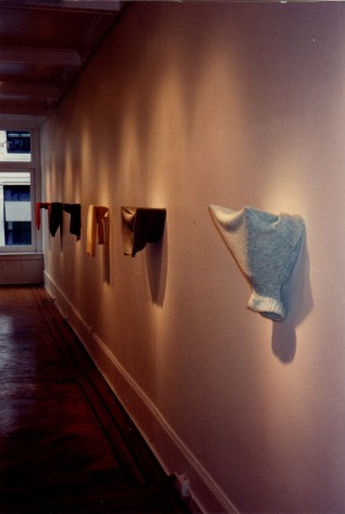 Sweaters hung from gallery wall