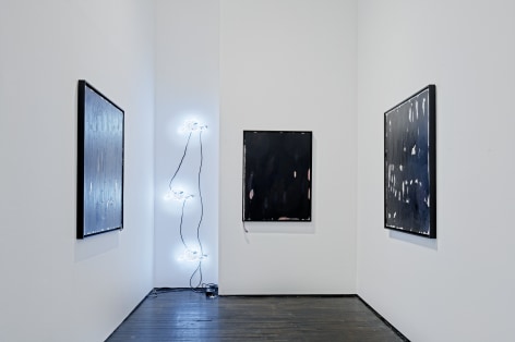 Gallery view of paintings and neon light
