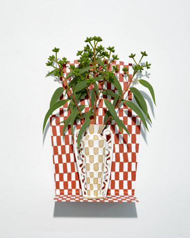 White patterned vase holding flora, on red and white patterned shelf.