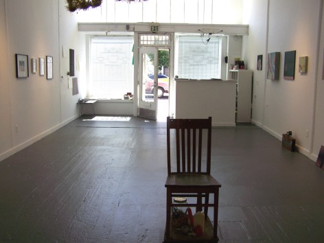 Installation view of gallery entrance, with wooden chair