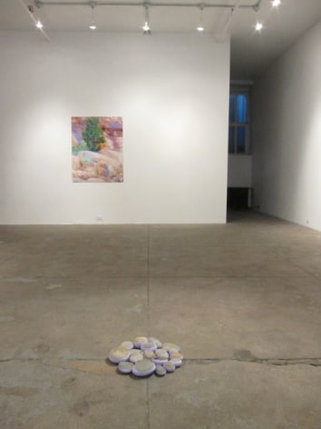 Installation view featuring rock pile and painting