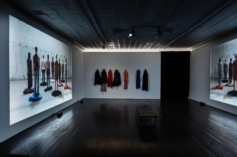 Installation view showing darkened gallery with projectors displaying images on gallery walls