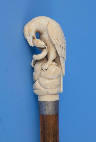 Cane with carved Ivory grip featuring a highly detailed carving of a Eagle clutching an open mouth serpent with spit tongue in his talons. The cane has a silver spacer with hallmarks. American or English circa 1890