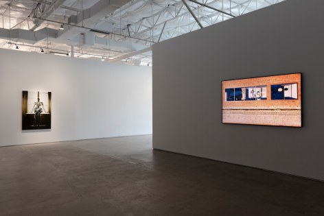 Installation view of Yifan Jiang's 2 channel video installation Neighbors, showing a single screen and the painting Late Afternoon
