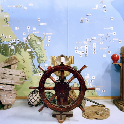 Color photo showing a museum display with an old fashioned captain wheel from a sailing ship