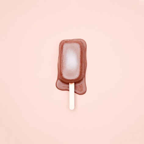 Color photo of a popsicle melting on a pink background.