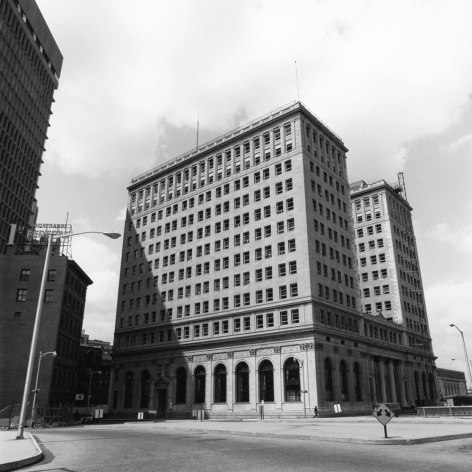 Black and white photo of a large early 20th century building in a deserted corner of a downtown area.
