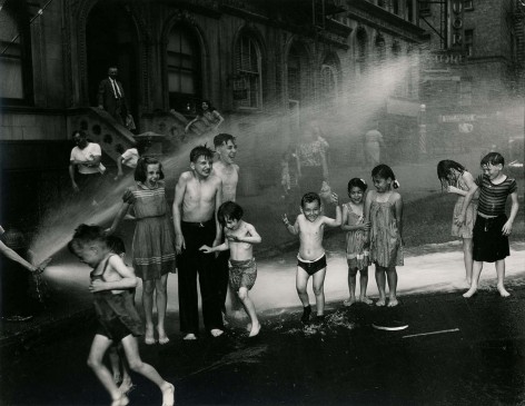 Black and white photo of young children playing in fire hydrant spray.