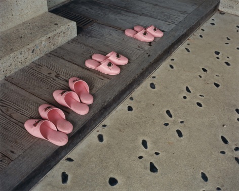 Photo os Japanese slippers left at a threshold in front of concrete steps.