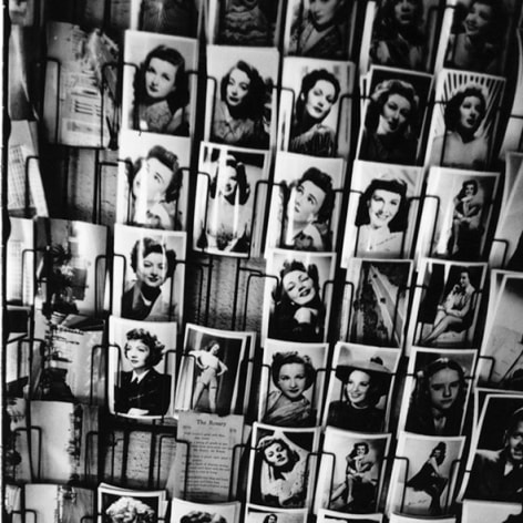 Black and white photograph of a rack of postcards featuring glamor shots of 1950s Hollywood actresses