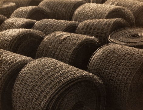 Black and white photo: Bales of rolled industrial wire filling the image area.