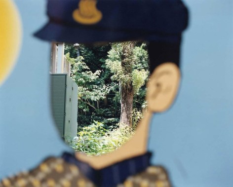 Photo of an empty &quot;photo op&quot; that depicts a cartoon policemen, the place to put your face is empty, so the forested background is seen through the face hole.