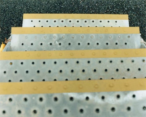 Color photo of metal seps with yellow stripes leading to a gravel covered surface.