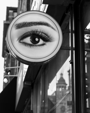 Black and white onto of a shop sign featuring a single eye.