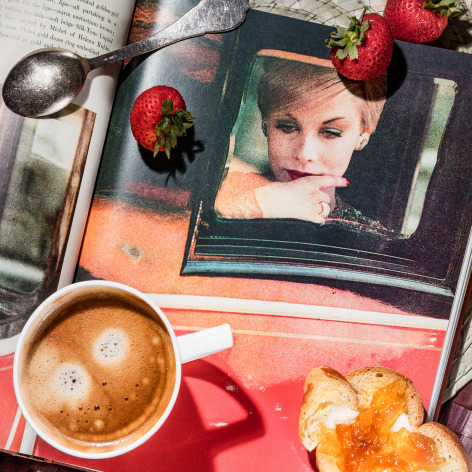 Photo image of a breakfast table with coffee and and an open book showing a color photograph by Saul Leiter.