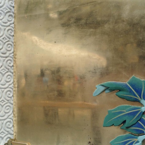 Close-up photo showing a gold leaf surface with decorative carvings and tile leaves around it.