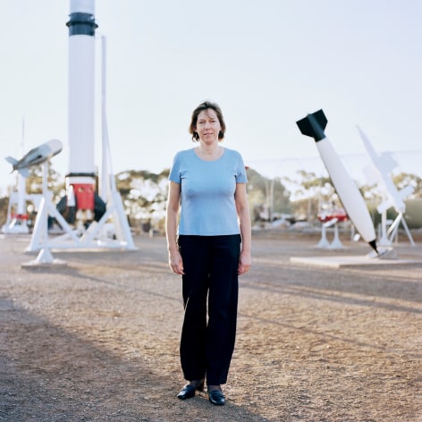 Woman standing outside next to display of missiles