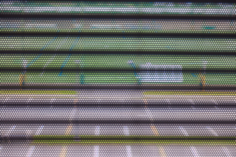 Color photo showing a colorful outdoor scene glimpsed through grating.