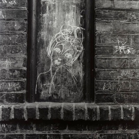 Black and whtie photo of a chalk drawing of a woman drawn in a frame on a brick wall