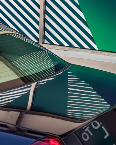 Photo of a colorful scene showing a striped reflection on a parked car.