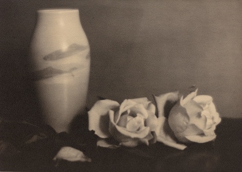Black and white image: Vase decorated with fish alongside two roses