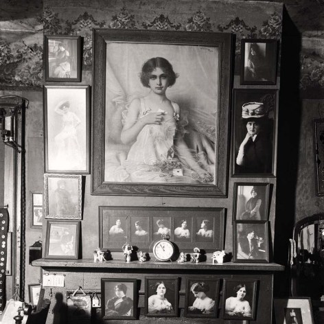Vintage black and white photo of a mantel surrounded by female portraiture. 