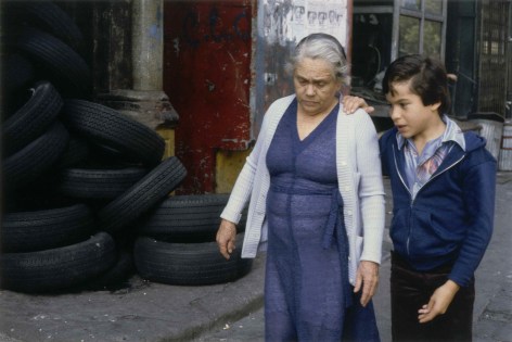 Color photograph of a young boy talking to an older woman with his hand on her shoulder.