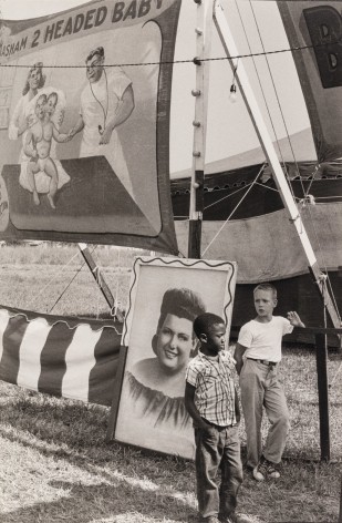 Black and white phoso of a young black boy and a a young white boy at a carnival side who in 1960.