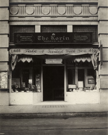 Black and white photo of the The Koran, a storefront Kodak Store based in LA in the 1920s&mdash;framed pictures are in the shop windows and there is an awning that reads &quot;Take a Kodak With You&quot;