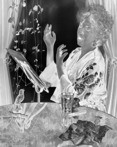 Black and white photographic negative of a woman singing at a table with a statue of a bird.