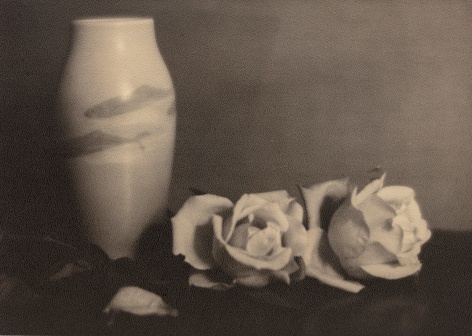 Black and white still life with vase decorated with Japanese koi and white roses next to it.