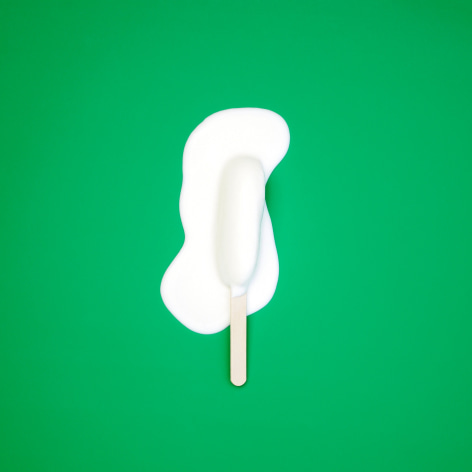 Colorful photo of a melting popsicle on a solid green background.