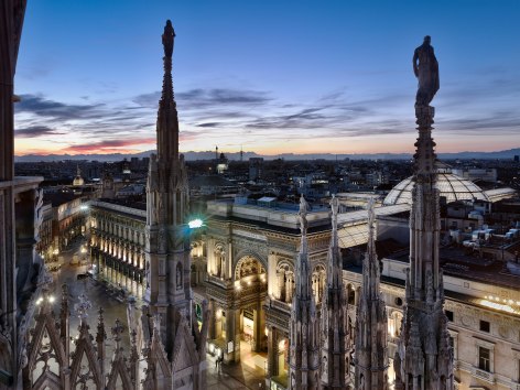 Photo of dramatic cathedral spires looking down on Milan, Italy at night.