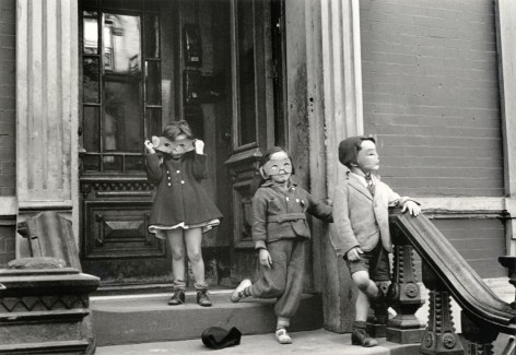 Black and white photo of three kids on a NYC stoop wearing masks.