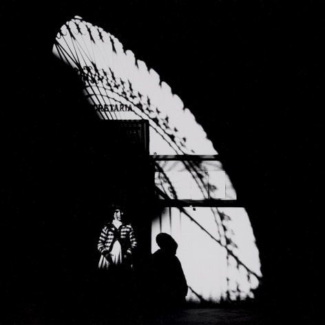 Black and white photograph by Ray Metzker showing a child in light and sad from a grilled doorway in Spain—shot in 1960