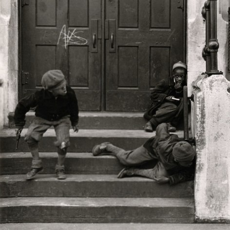 Back and white photo of three young black boys on a stoop playings with toy guns.