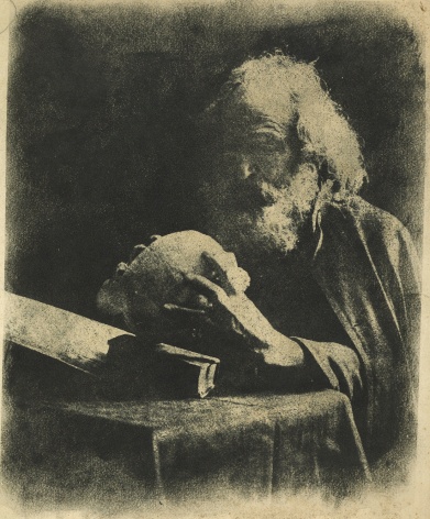 Black and white photo of an old bearded man examining a skull.