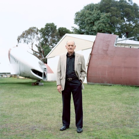 Man standing outside in old airfield with vintage airplane