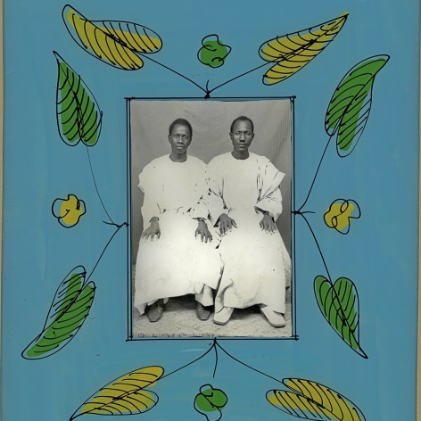 Black and white photo portrait of two African men sitting in white robes, framed in colorful blue frames with hand painted yellow and green leaves. 